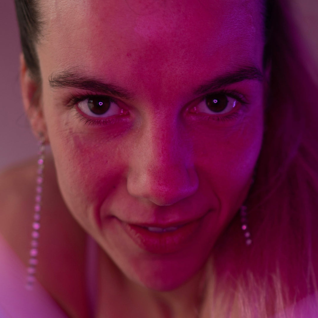 Close up billede af person hvor man kan se et lyserødt hjerte lys blive spjelet i deres øjne.