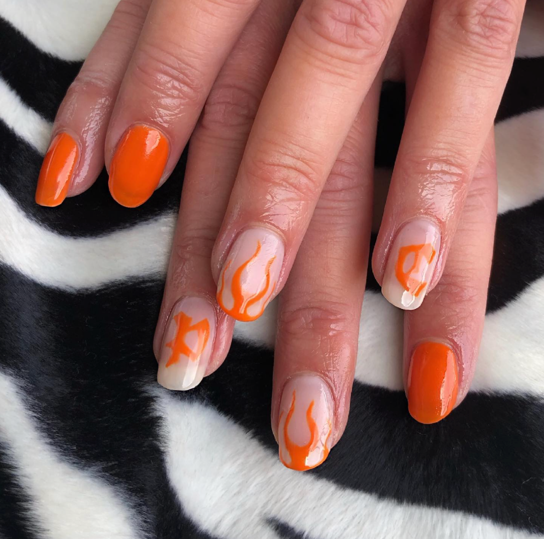 Nailart i orange med blackletter bogstaver og ild.