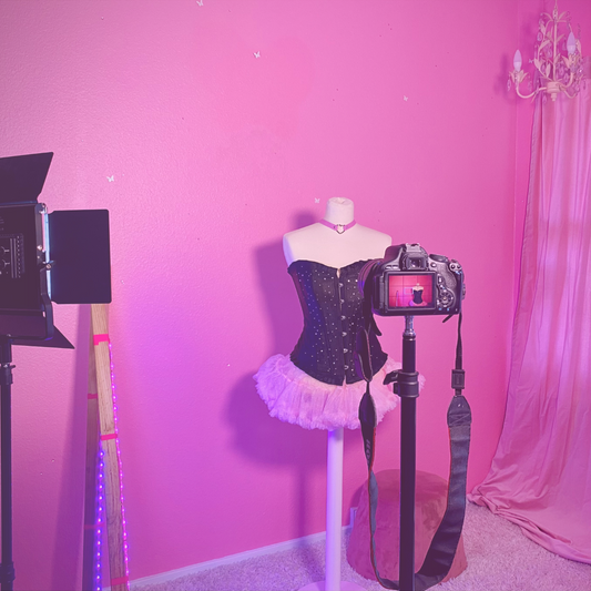 Billede af maniquin i korset og tylskørt der bliver fotograferet i lyserødt feminiseringsstudie til crossdressers og trans femmes i København